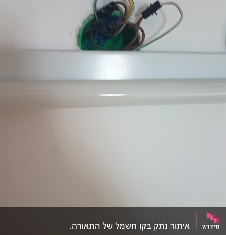 חוטי חשמל מחוברים לקופסת חיבורים בקיר